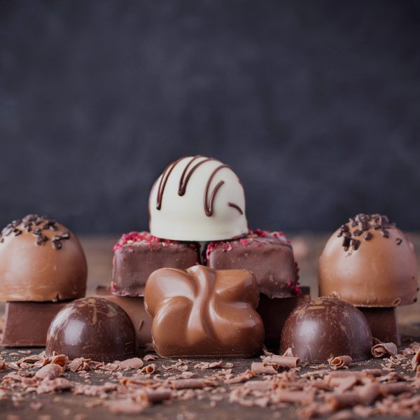 Traditional Belgian chocolate variety over rustic wooden board, decorated with chocolate swirls.